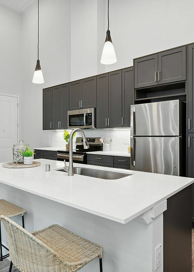 Modern kitchen with sleek dark cabinets, stainless steel appliances, and a spacious white island, offering a blend of style and functionality.