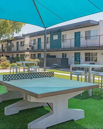 Vibrant outdoor space with modern table tennis, stylish seating, and lush greenery, perfect for recreation and relaxation in a contemporary apartment community.