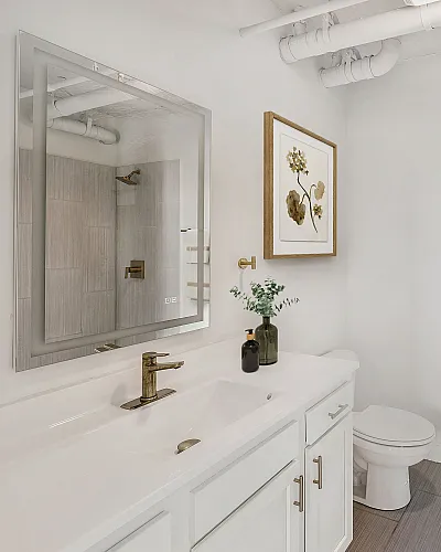 Elegant bathroom featuring a sleek white vanity, modern fixtures, and tasteful wall art, exuding a luxurious and serene atmosphere.