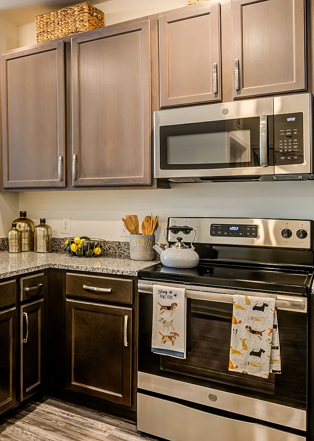 Chic open-concept kitchen and living space featuring elegant dark cabinetry, modern appliances, and vibrant blue seating, creating a welcoming and stylish atmosphere.