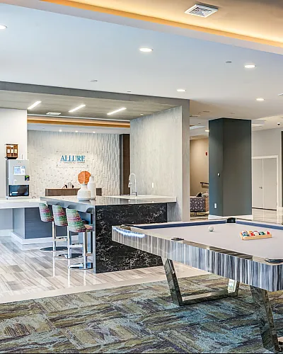 Chic and spacious recreational lounge featuring a sleek billiards table, modern bar seating, and ambient lighting, perfect for relaxation and entertainment.