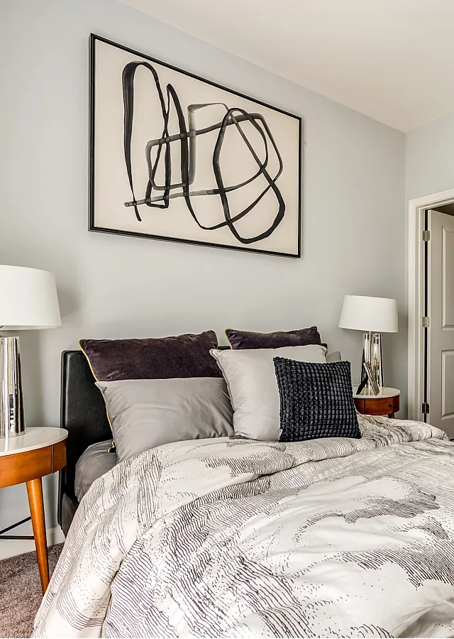Modern bedroom with stylish decor, plush bedding, and elegant lighting leading to a chic bathroom, exuding comfort and sophistication.