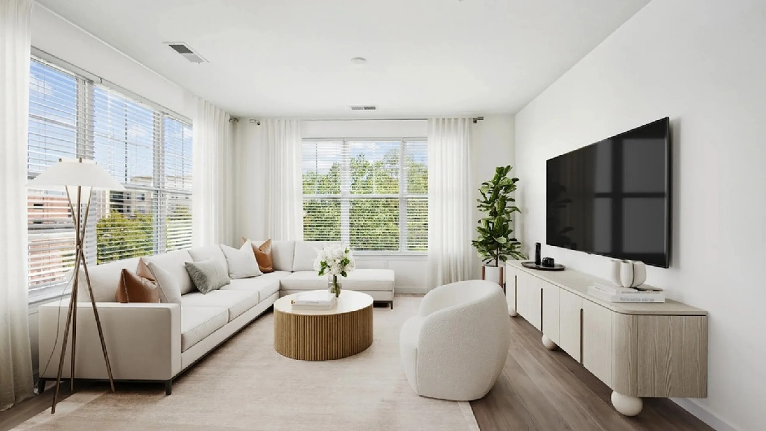 Elegant living room featuring a cozy sectional sofa, modern round coffee table, and a sleek wall-mounted TV, accented by large windows with serene natural light.
