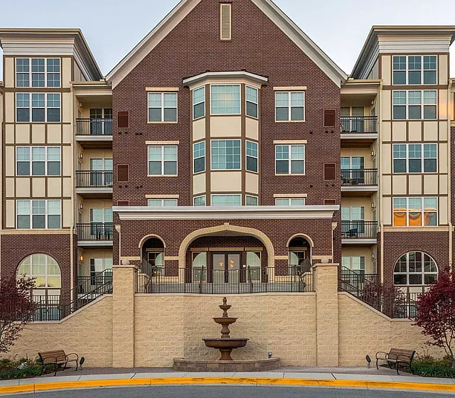 Elegant apartment building with modern design, featuring a grand entrance, abundant windows, and lush landscaping.