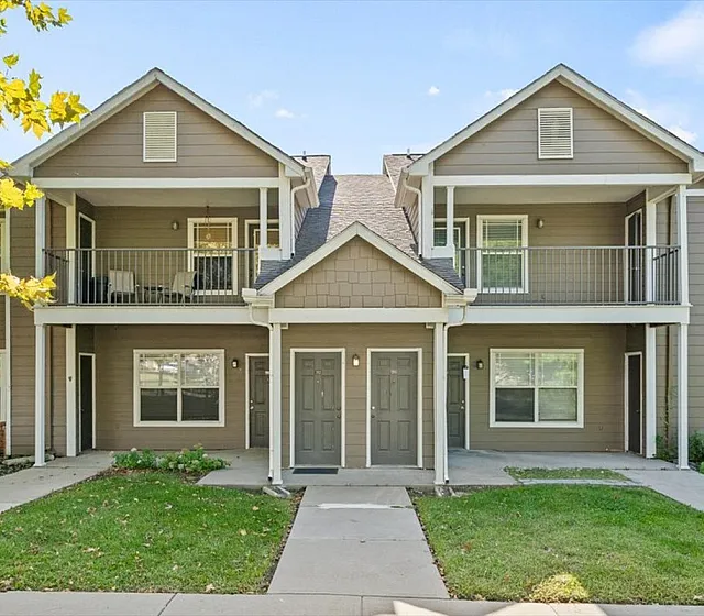 Charming two-story apartment building with private balconies and well-maintained green lawns, perfect for serene living.