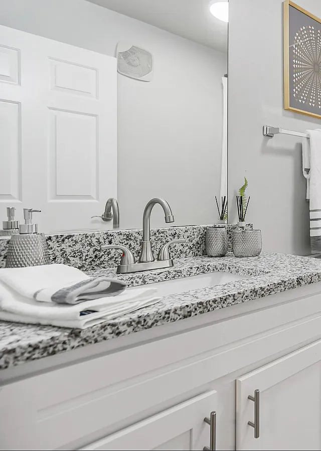 Elegant bathroom with modern granite countertop, pristine white fixtures, and stylish decor.