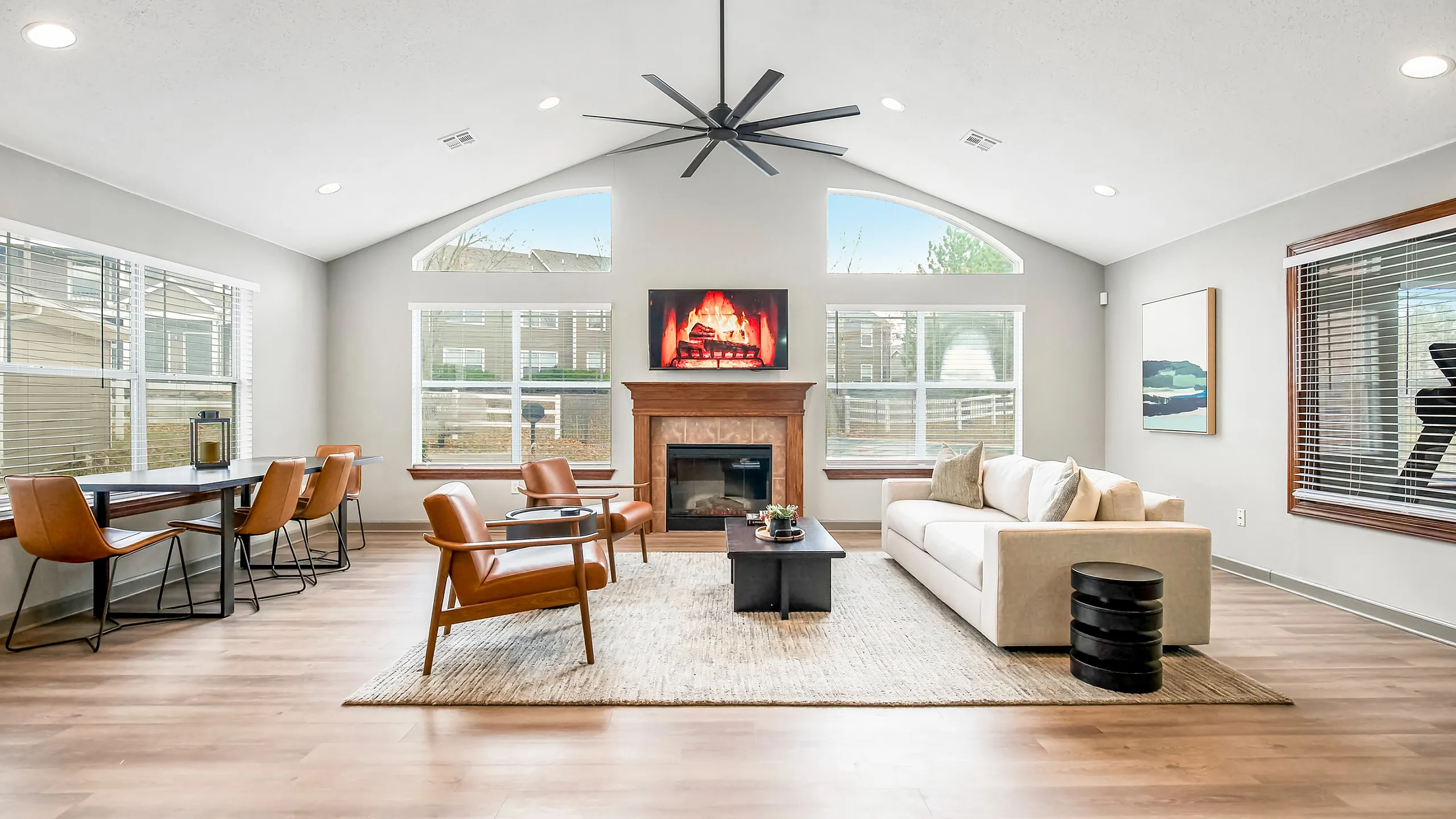Inviting open-concept living room with modern furniture, cozy fireplace, and large windows offering abundant natural light.