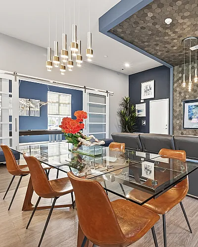 Elegant open-concept living area with a modern glass table, stylish leather chairs, chic lighting fixtures, and contemporary wall art, perfect for entertaining.
