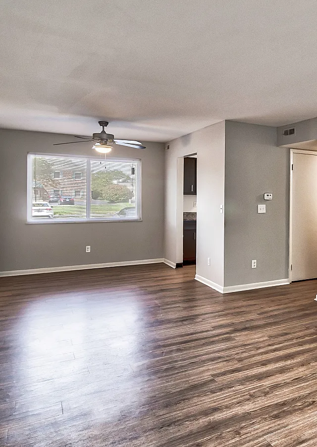 Bright apartment interior featuring elegant hardwood flooring, a ceiling fan, and a welcoming open space perfect for modern living.