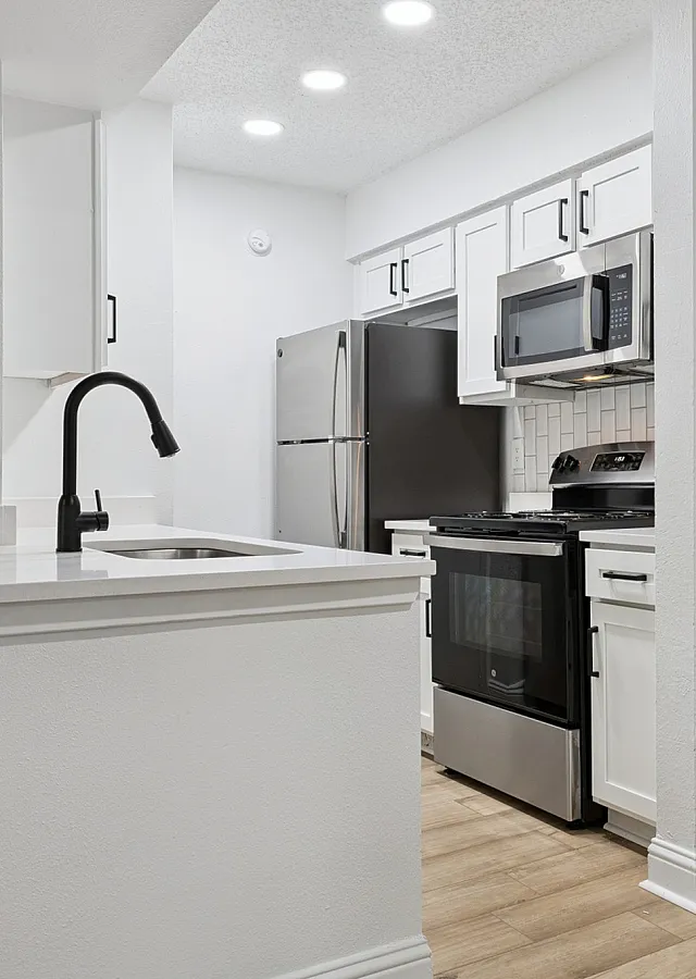 Modern kitchen with sleek stainless steel appliances, stylish white cabinetry, and elegant countertops under bright recessed lighting.
