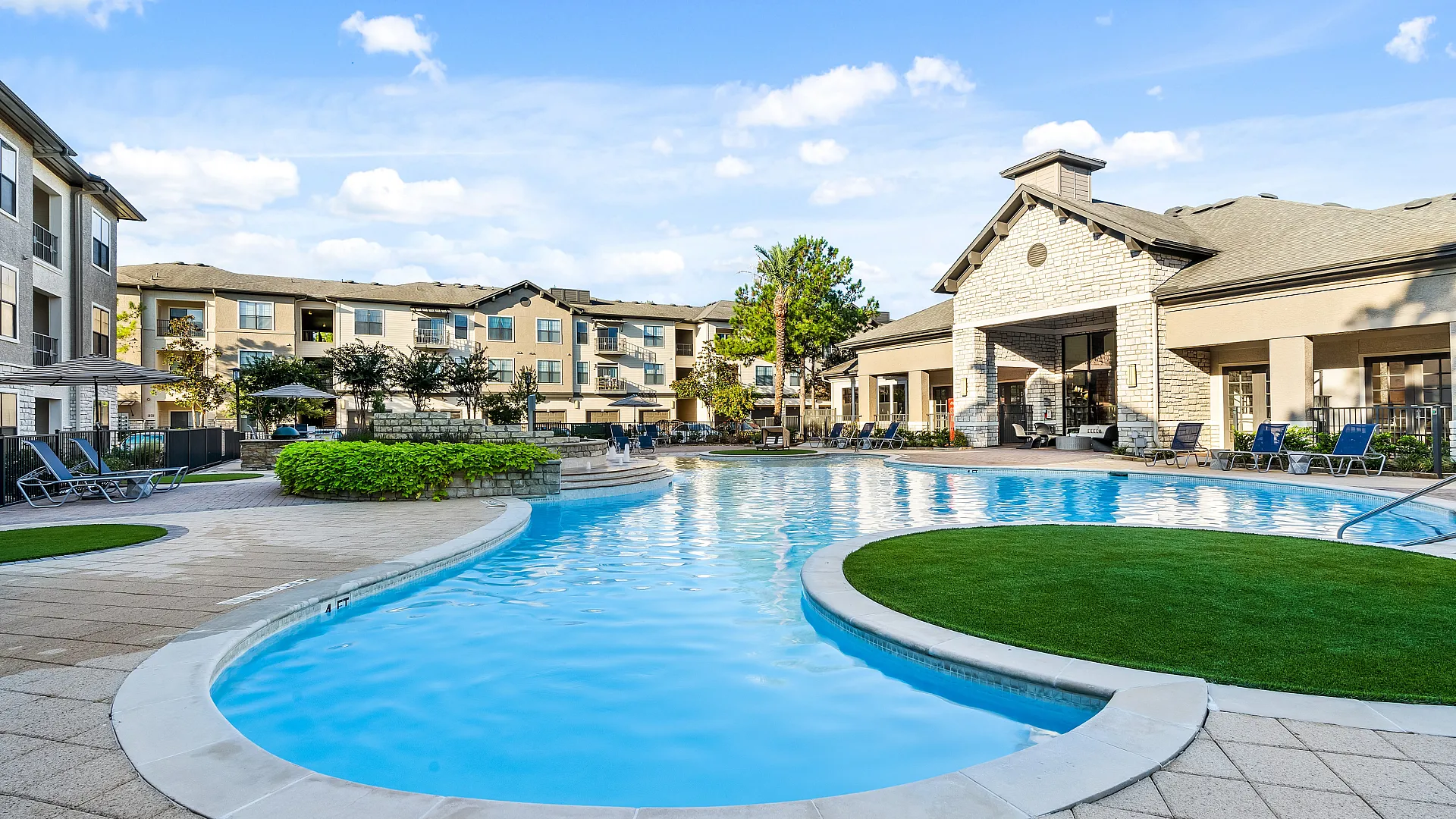 Luxurious apartment complex with resort-style swimming pool, surrounded by lush greenery and modern architecture.