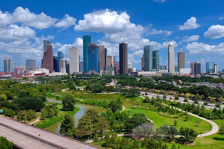 Stunning aerial view of city skyline with lush green park and clear blue skies, showcasing urban living blended with nature.