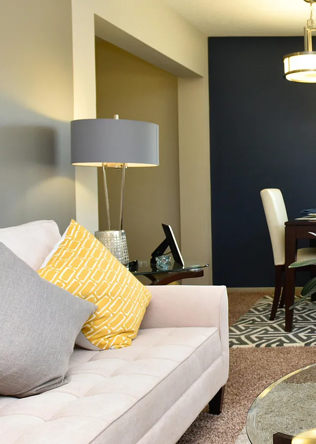 Modern living room with plush beige sofa, elegant dining area, and chic decor in an open-concept space.