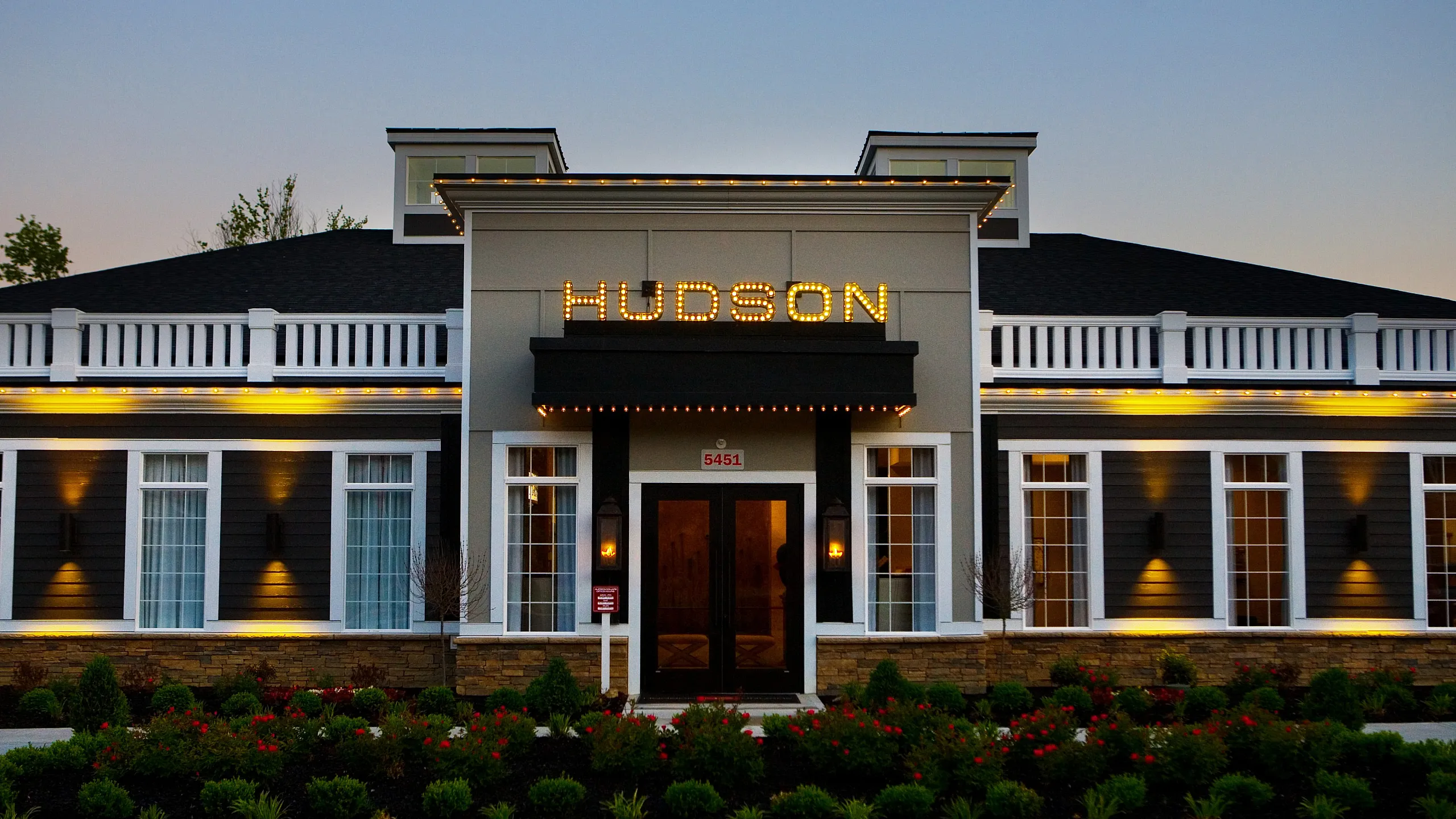 Elegant apartment building facade at dusk with modern lighting and lush landscaping.