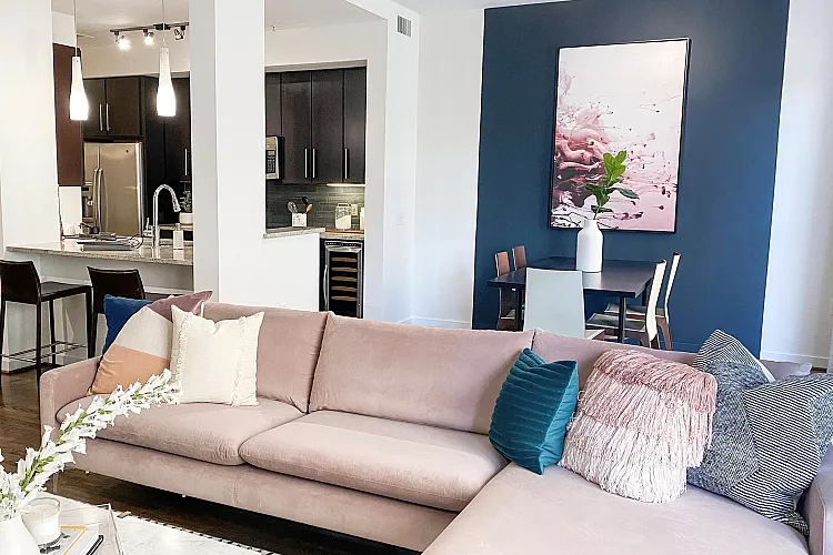 Chic modern living space featuring a plush pink sofa, elegant dining area, and sleek kitchen with contemporary lighting.