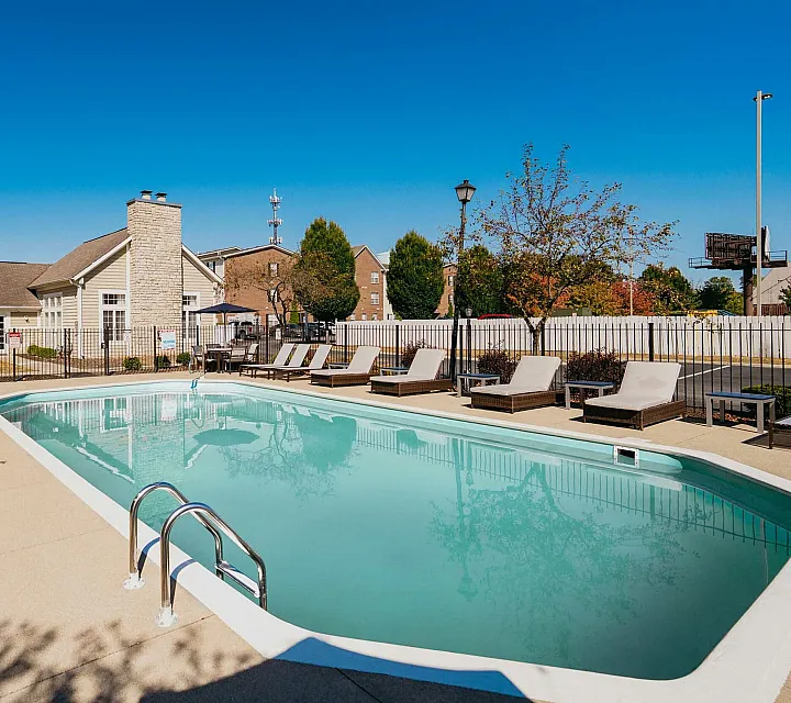Inviting outdoor pool area with stylish lounge chairs and clear blue skies, perfect for relaxation.