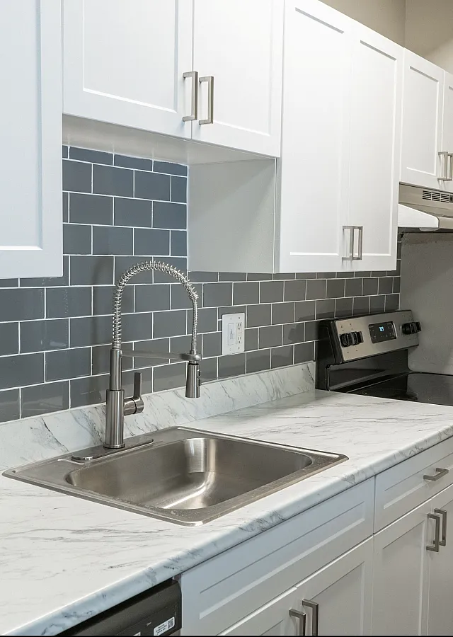 Modern kitchen with sleek gray subway tile backsplash, elegant marble countertop, and stainless steel appliances.