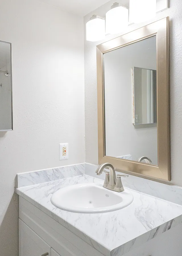 Elegant bathroom with a sleek marble countertop, modern white sink, and sophisticated lighting.