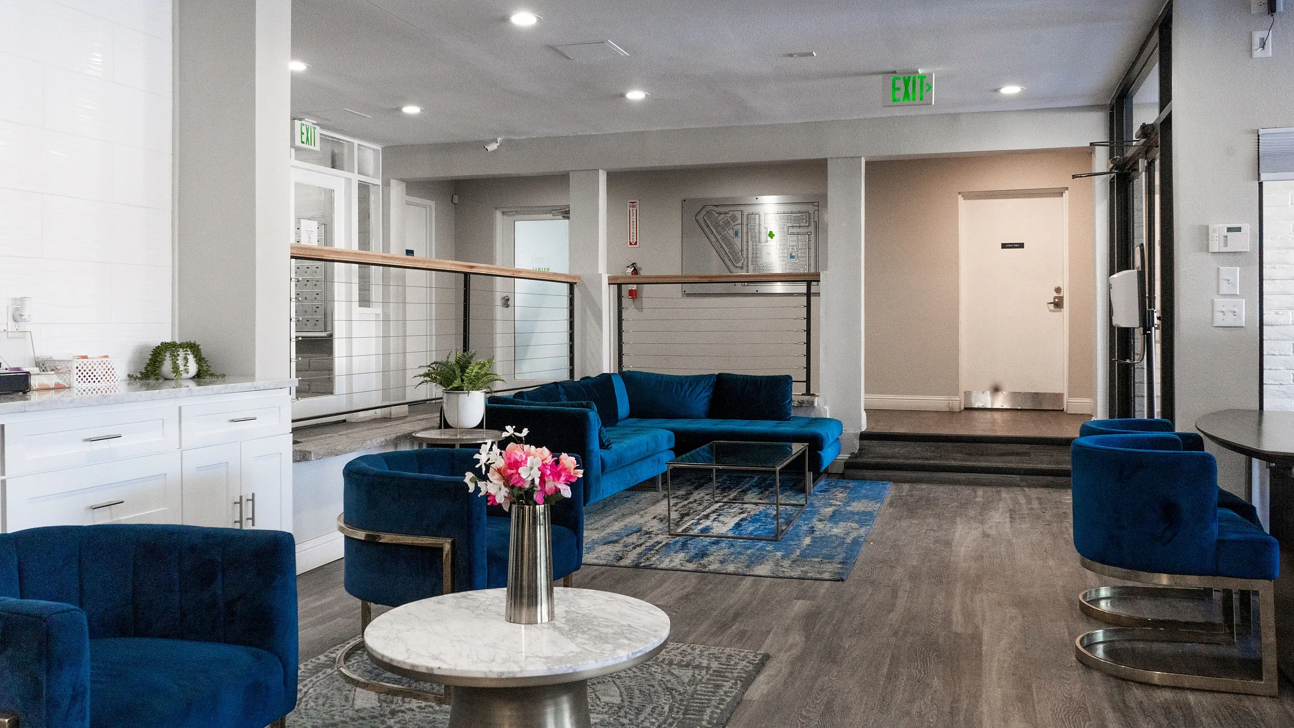 Elegant lobby with plush blue velvet seating, modern decor, and chic marble tables, offering a stylish and welcoming ambiance.