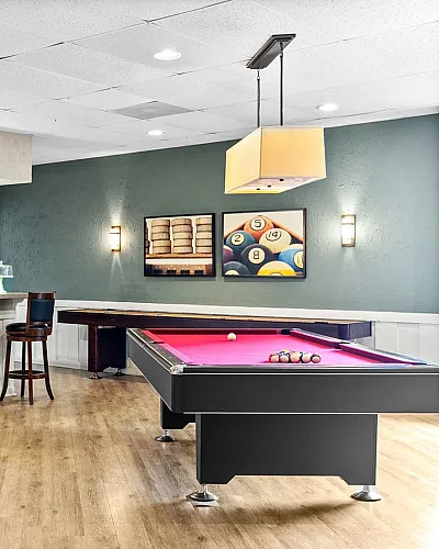 Inviting recreation room featuring a sleek billiards table, stylish bar area with high-top seating, and modern decor.