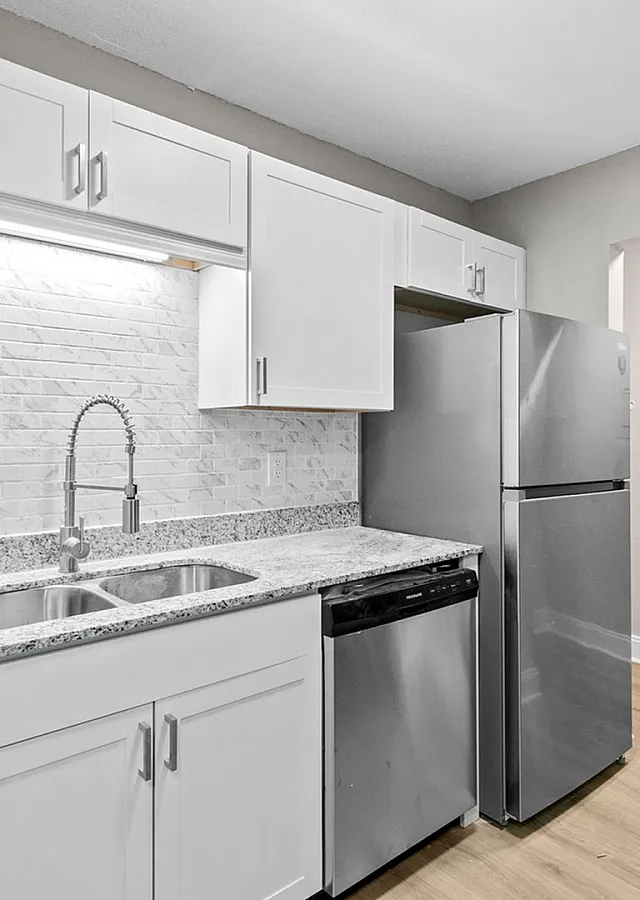 Sleek modern kitchen with granite countertops, stainless steel appliances, and elegant white cabinetry.