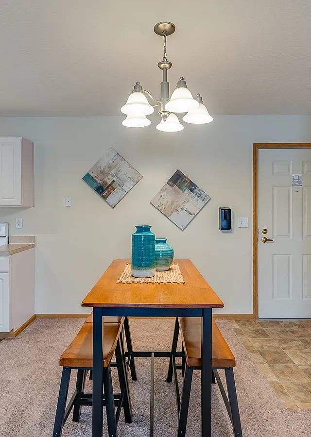 Cozy open-concept kitchen and dining area with modern lighting, elegant decor, and vibrant potted plants for a touch of nature.