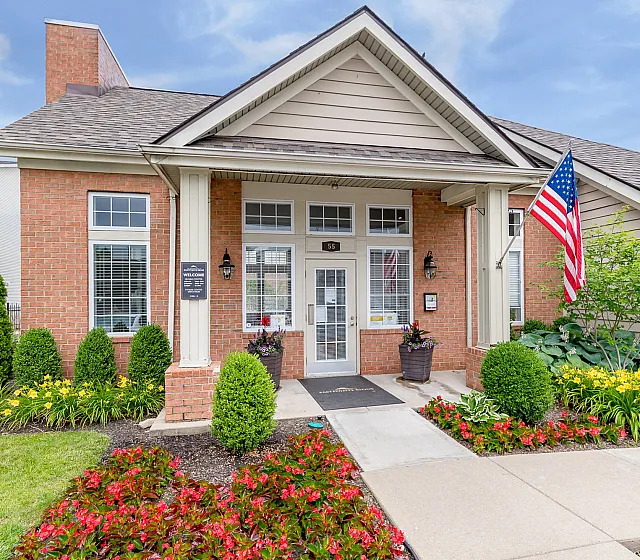 Charming brick exterior with beautiful landscaping and American flag, offering a welcoming entrance to a desirable community.
