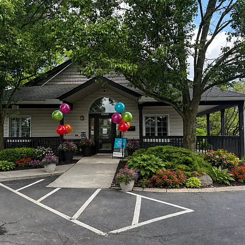 Charming apartment community entrance adorned with colorful balloons and vibrant landscaping, creating a welcoming and festive atmosphere.