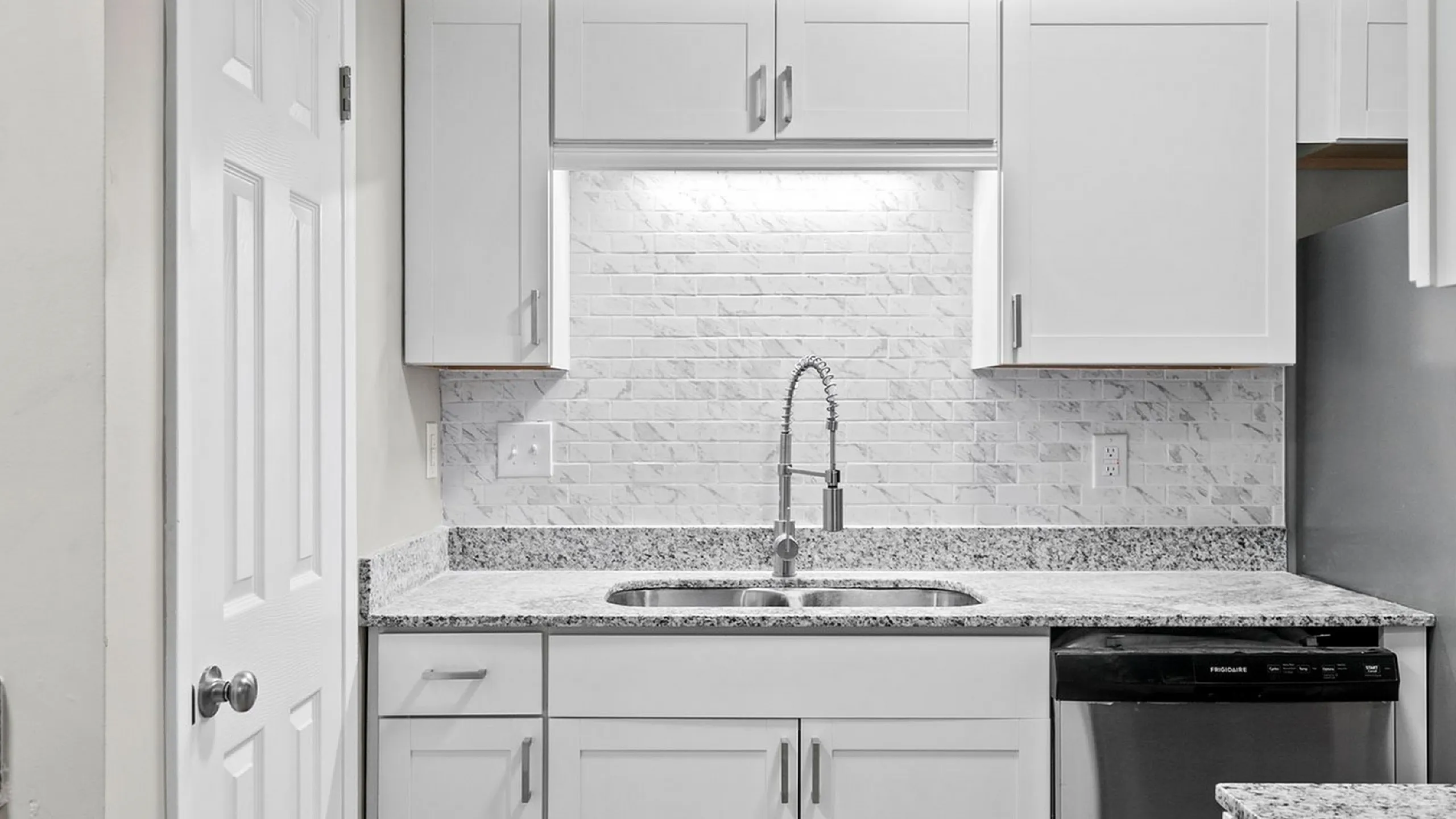 Modern kitchen with sleek white cabinets, granite countertops, and stainless steel appliances for a stylish cooking experience.