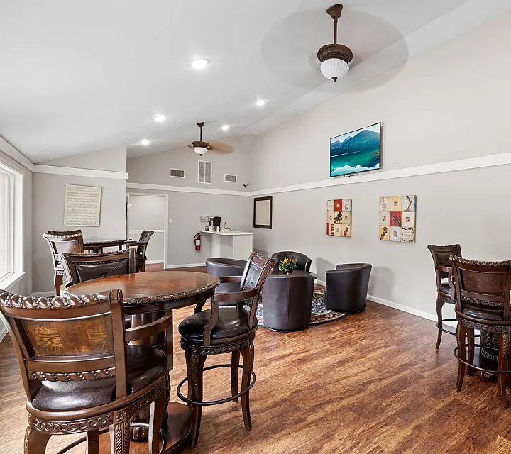 Elegant clubhouse lounge with stylish high-top tables, cozy seating area, and modern decor, ideal for social gatherings.