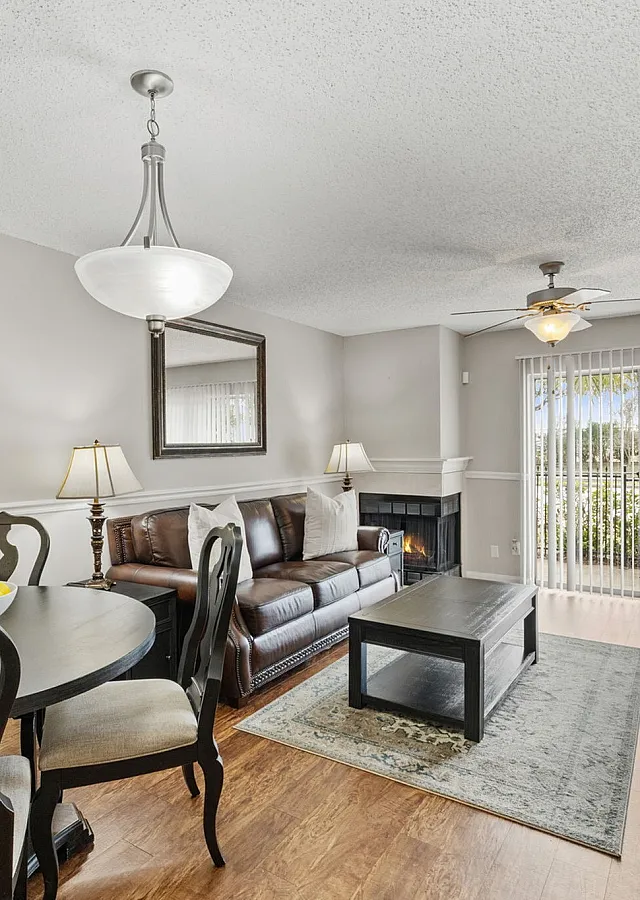 Bright and inviting living area with elegant hardwood floors, cozy fireplace, and abundant natural light through large sliding glass doors.