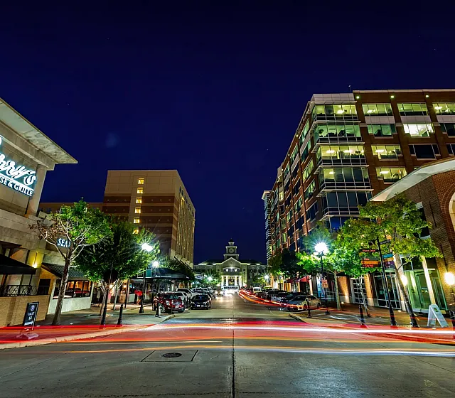 Vibrant urban night scene showcasing stylish apartments and lively street life, accented by a chic steakhouse in the foreground.