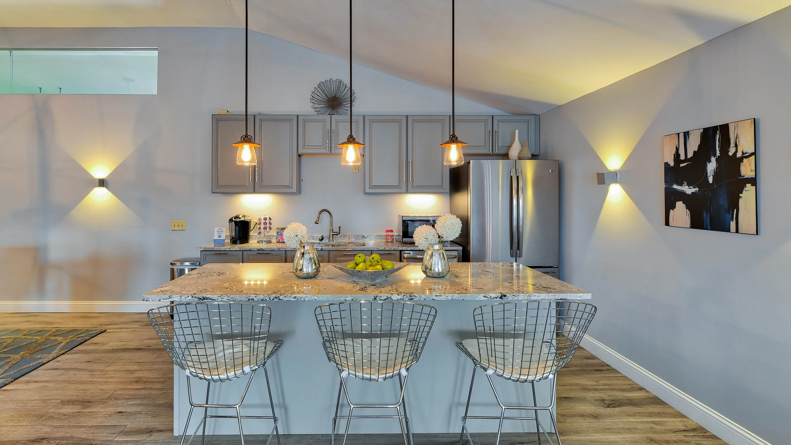 Inviting modern kitchen with elegant pendant lighting, sleek gray cabinets, and a spacious granite countertop perfect for entertaining.