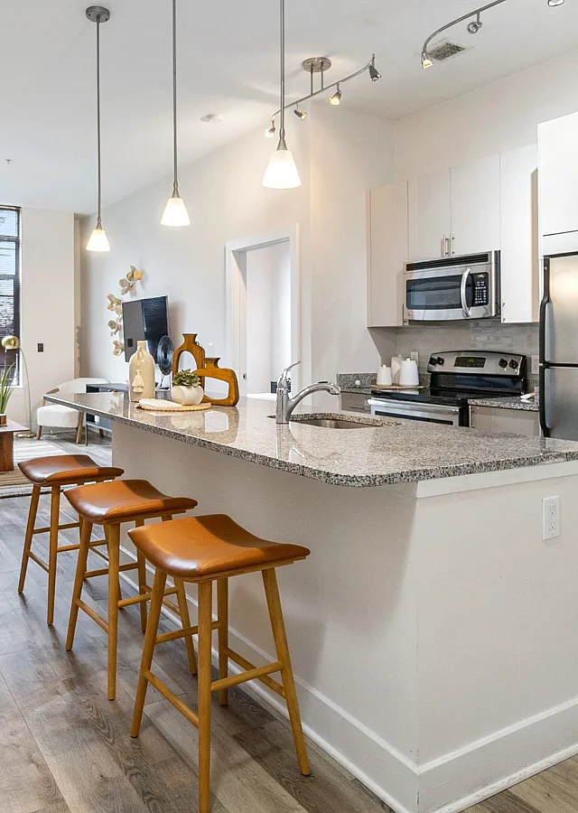 Elegant open-concept kitchen and living area with sleek granite countertops and modern stainless steel appliances, exuding a bright and welcoming ambiance.