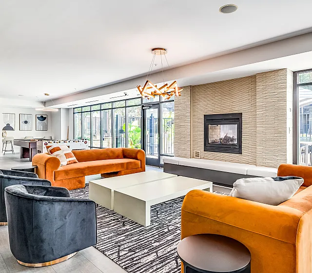 Chic apartment lounge with vibrant orange and navy seating, modern fireplace, and stylish lighting, perfect for relaxation and social gatherings.