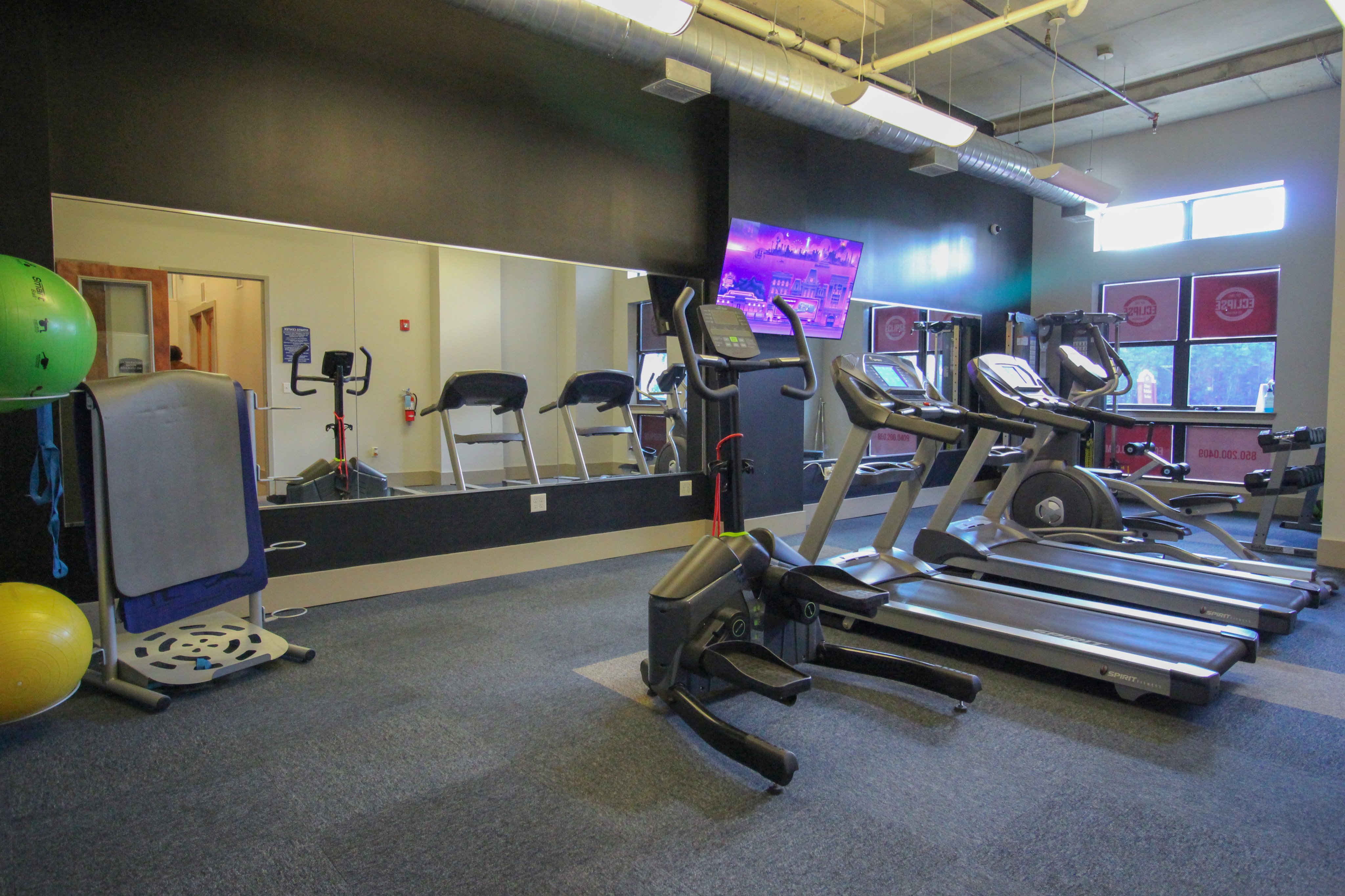 State-of-the-art fitness center with modern treadmills, exercise bikes, and gym equipment in a well-lit room.