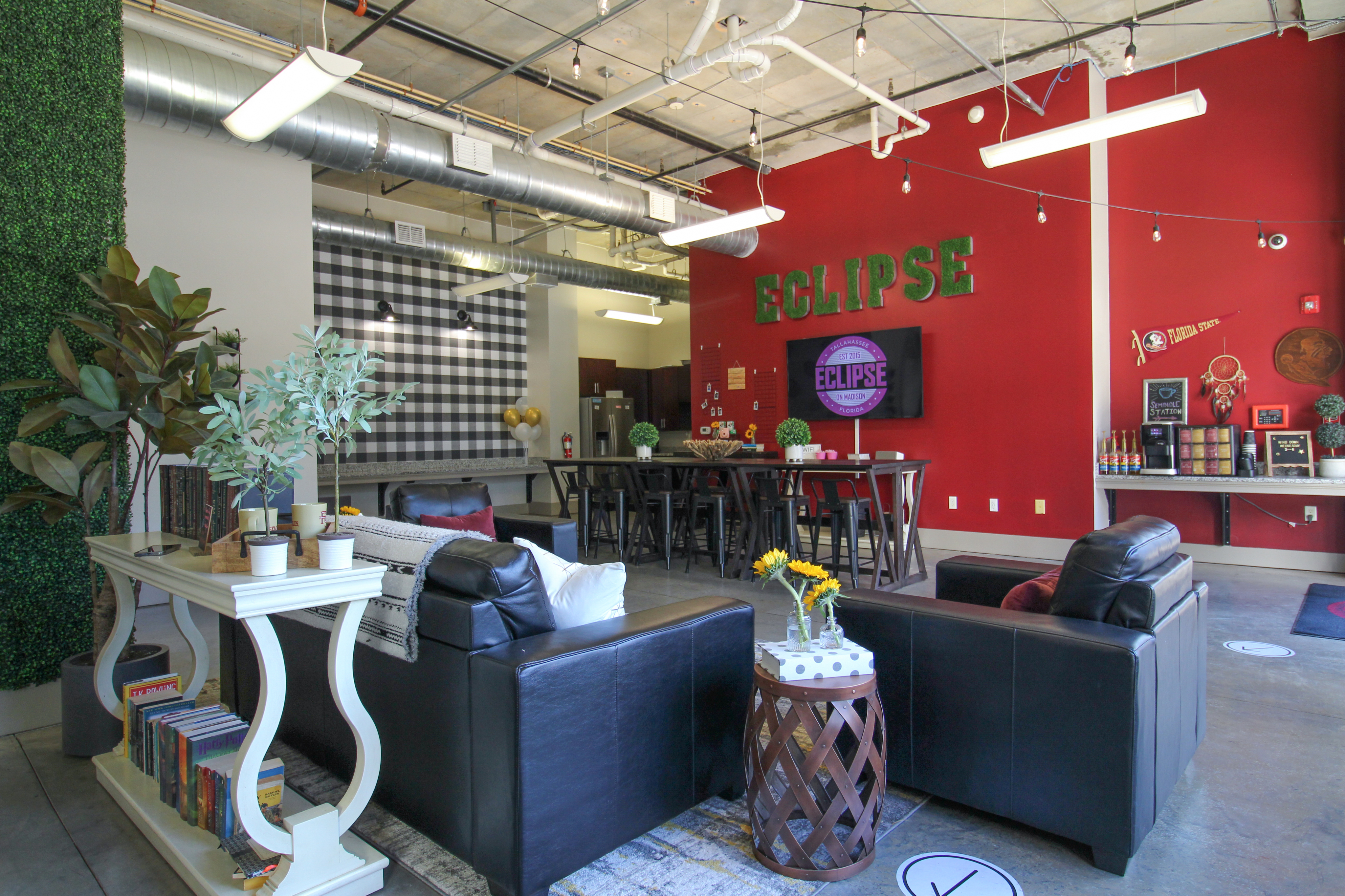 Stylish lounge with industrial decor featuring leather sofas, wooden tables, and a vibrant red accent wall.