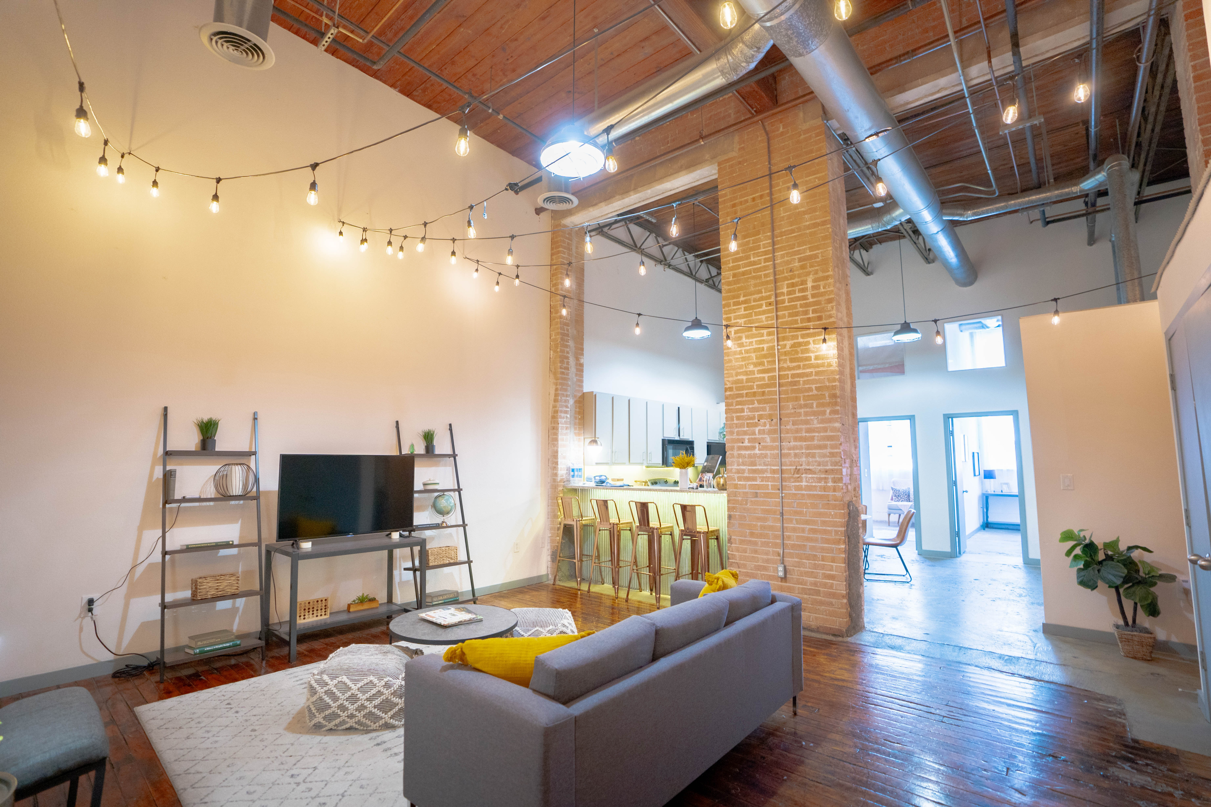 Stylish loft space featuring a modern living room with exposed brick, wooden floors, and ambient lighting.