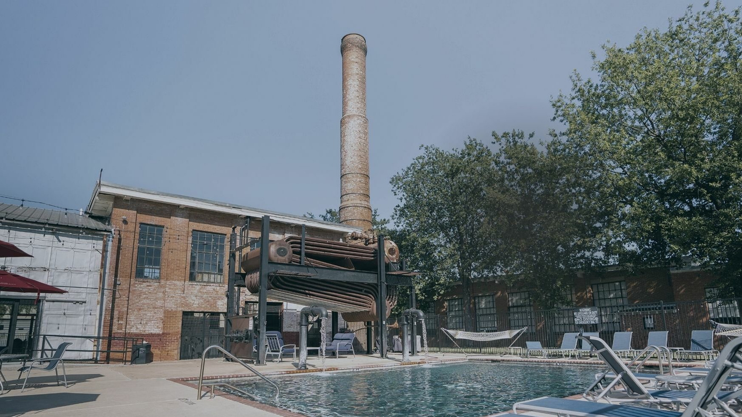 Inviting outdoor pool area with industrial-style architecture and cozy lounge seating.