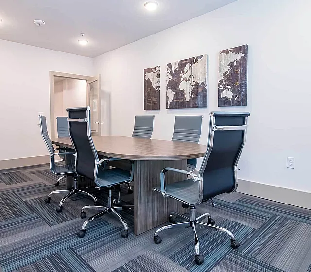 Modern conference room with sleek chairs, stylish wooden table, and world map decor, perfect for professional meetings.