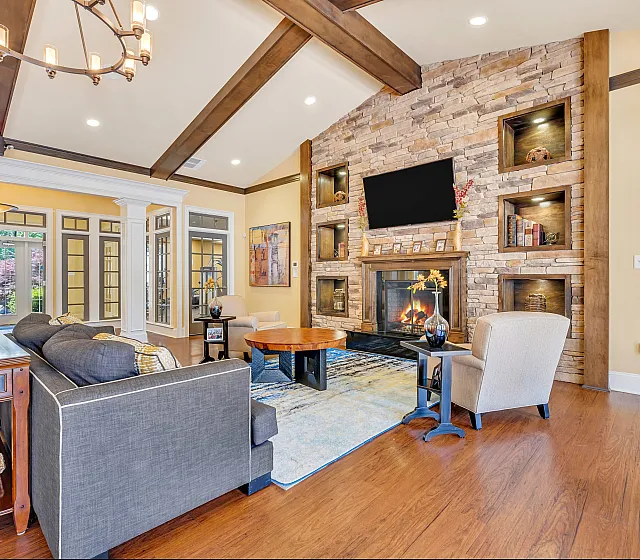 Elegant living room with rustic stone fireplace, cozy seating, and large windows inviting natural light.