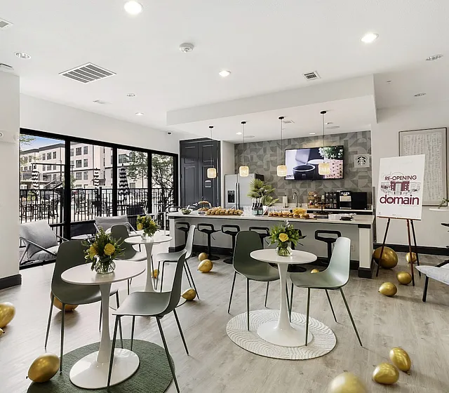 Chic communal space with modern decor, featuring stylish seating areas, elegant floral arrangements, and a sleek kitchen counter, creating a warm and welcoming atmosphere.