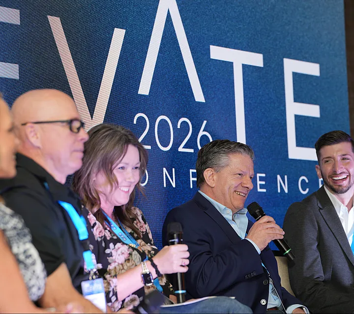 Dynamic panel discussion at the 2026 ELEVATE Conference featuring enthusiastic speakers engaged in conversation.
