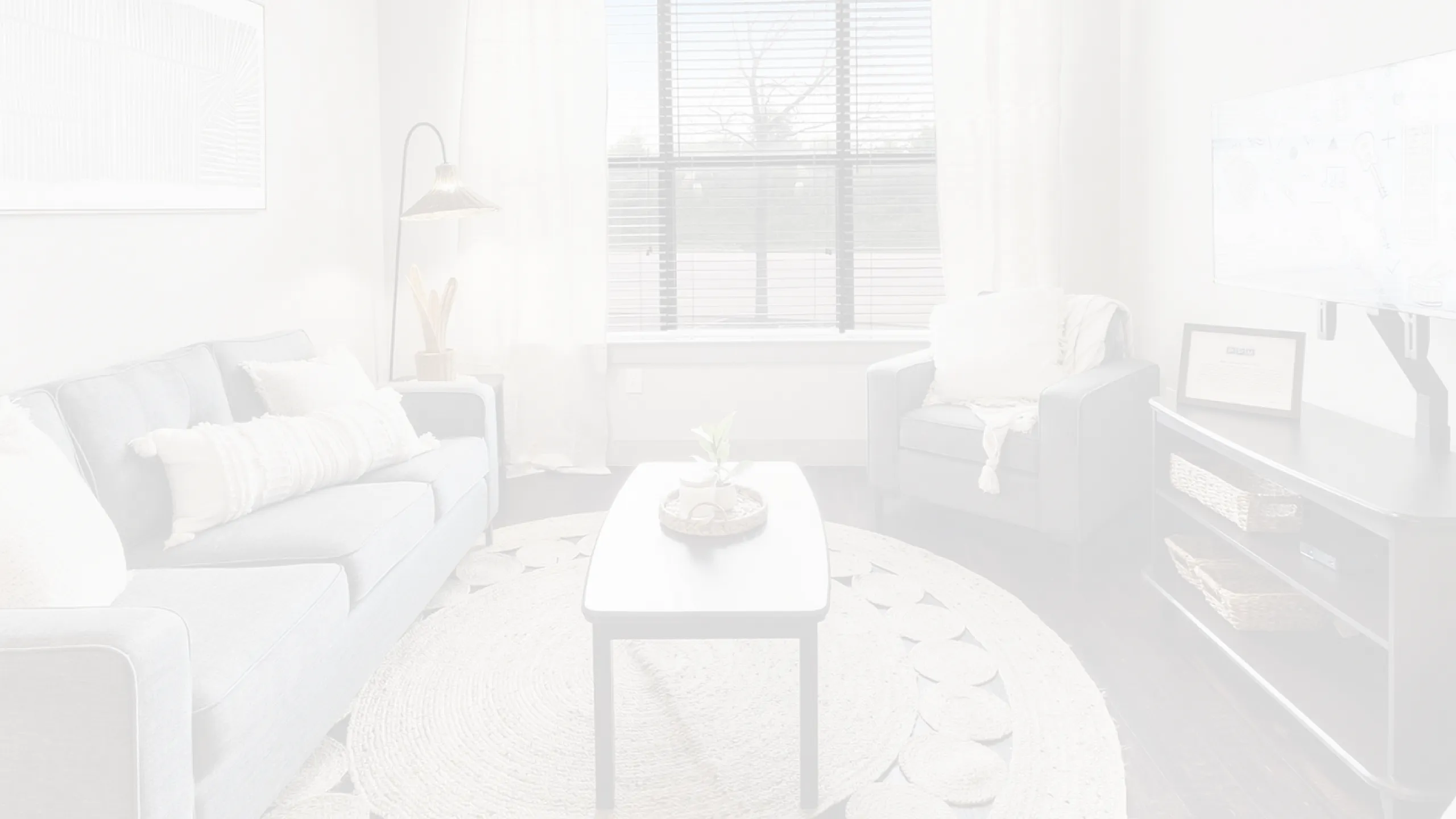 Bright and modern living room with stylish gray couch, chic armchair, and contemporary decor, featuring a large window for natural light.