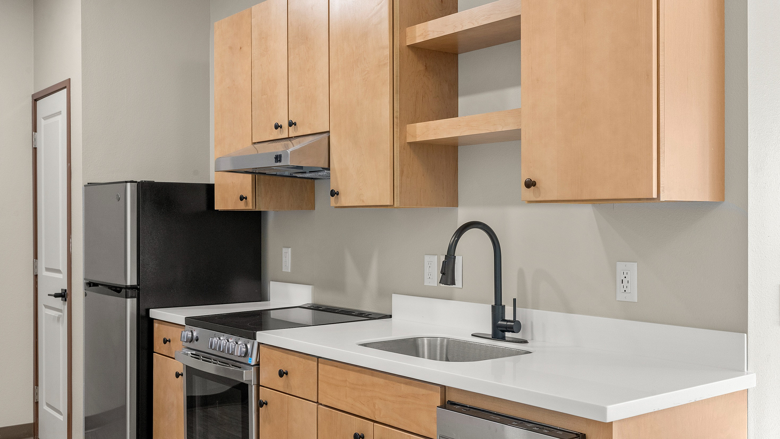 Modern kitchen with sleek stainless-steel appliances, light wood cabinetry, and elegant white countertops.