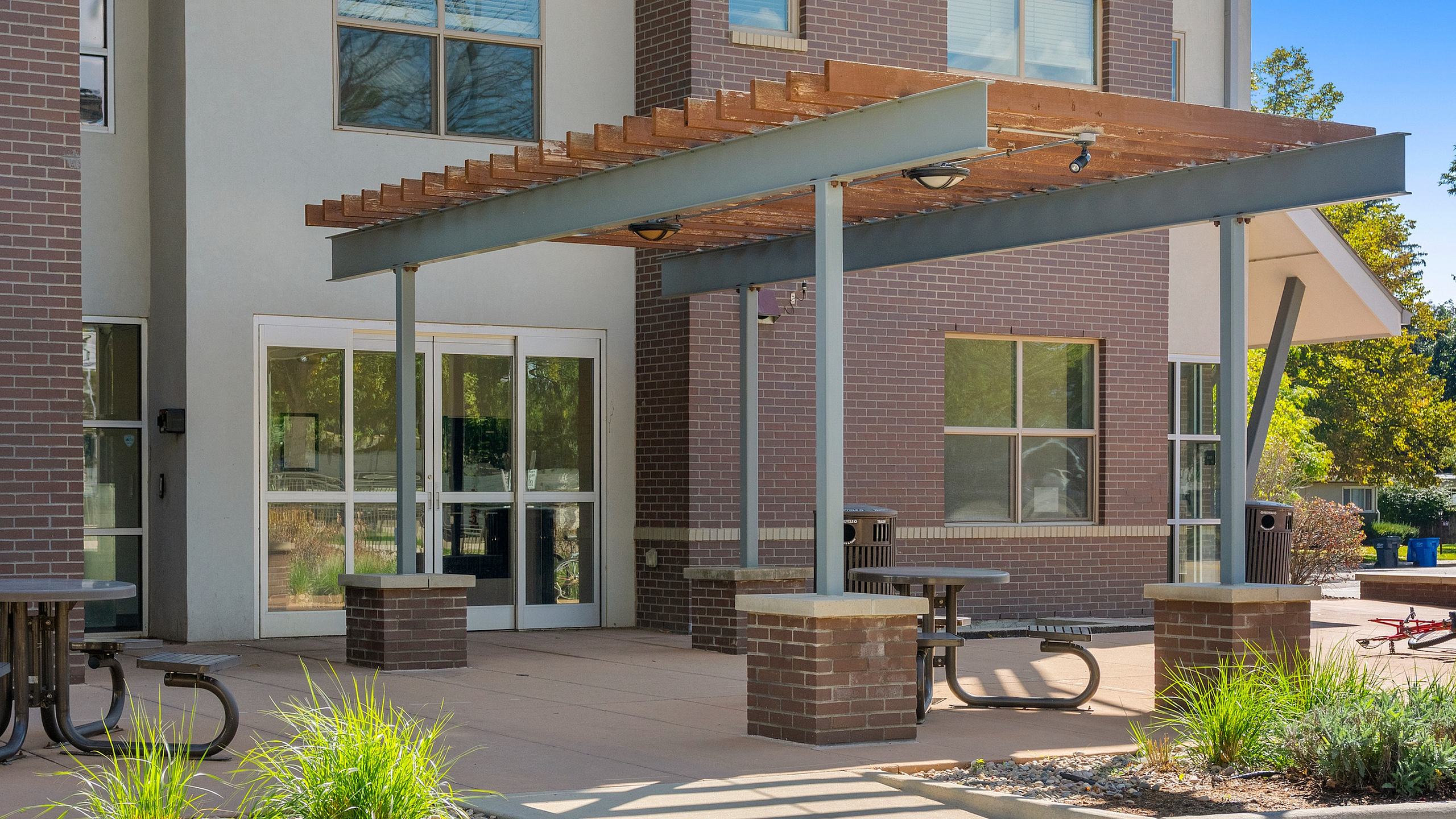 Charming outdoor patio area with modern pergola, perfect for relaxing in a stylish apartment complex setting.