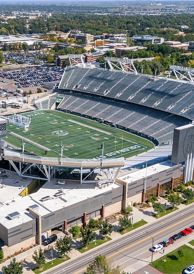 Aerial view of a modern stadium surrounded by lush greenery and a bustling urban landscape, ideal for sports events and gatherings.