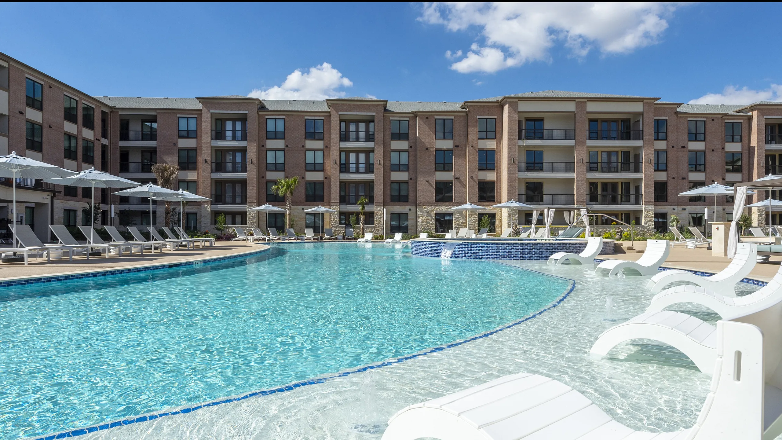 Inviting outdoor pool area with comfortable lounge chairs and modern apartment building in the background.