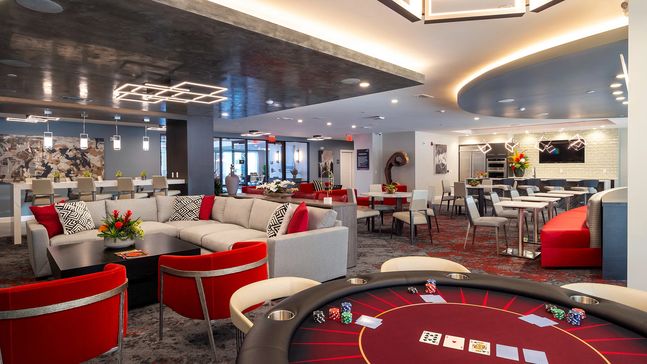 Luxurious and spacious entertainment lounge featuring modern decor, a poker table, plush seating areas, and stylish lighting accents.