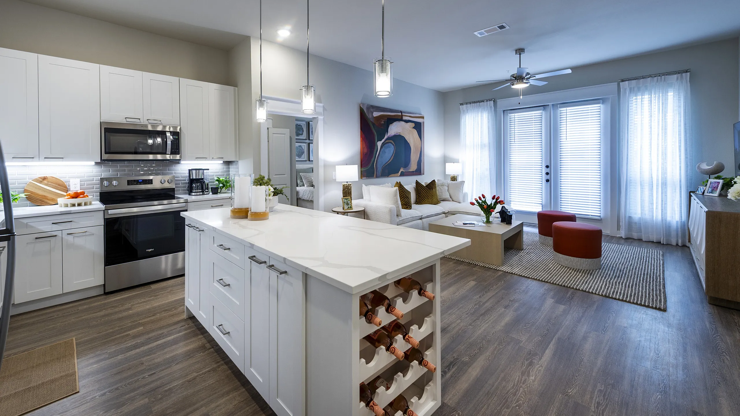 Modern open-concept living space featuring a sleek kitchen with white cabinetry and a spacious living area with elegant decor.